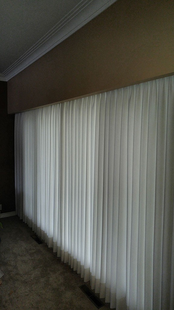 a long row of floor-length soft shades covering a window