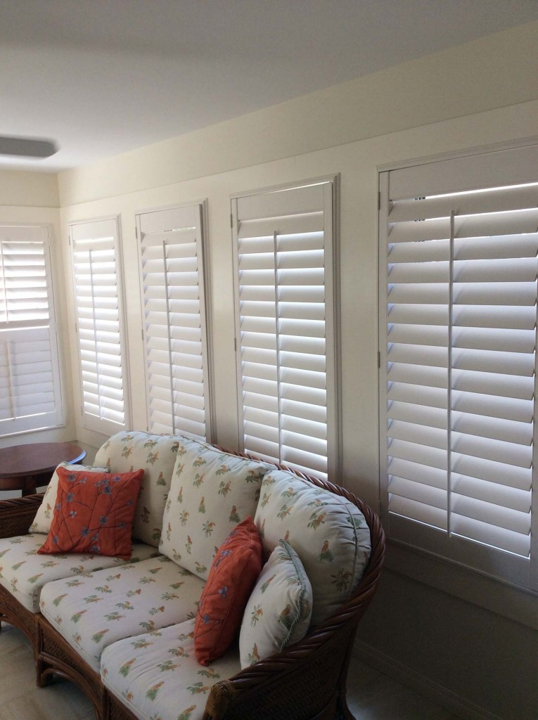 white shutters in a living room with large windows a plush white couch