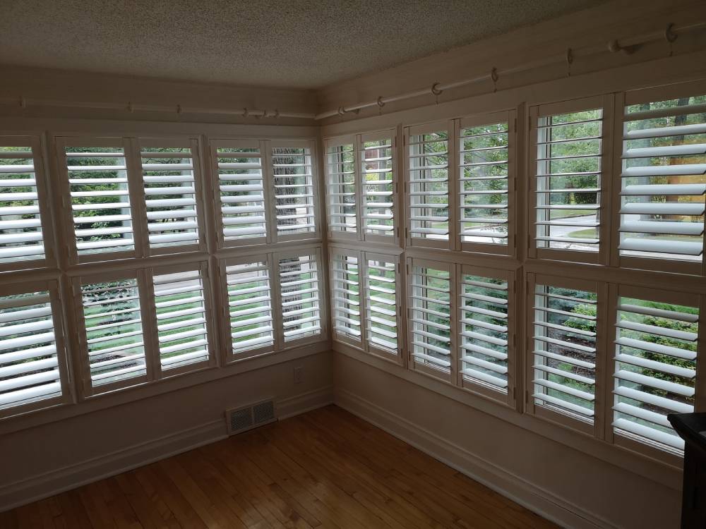 an empty room with white shutters and wood floors